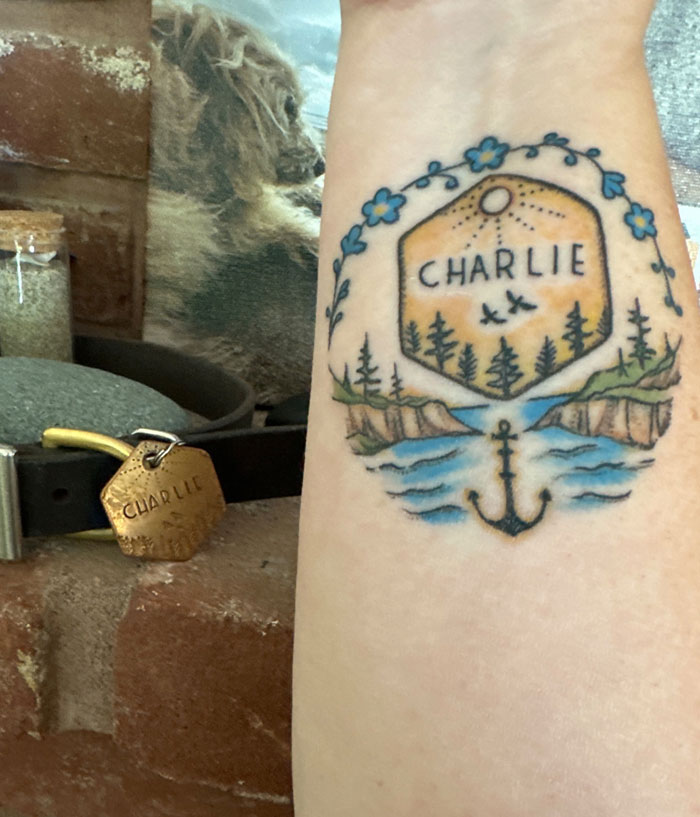 A colorful tattoo with a dog's name Charlie, surrounded by nature and ocean, symbolizing a meaningful bond.