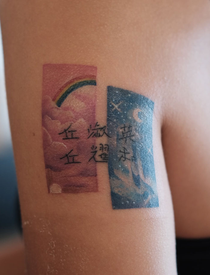 A colorful tattoo on an arm, split into two rectangular panels: one with clouds and a rainbow, the other with stars and text. These tattoos are deeply symbolic.