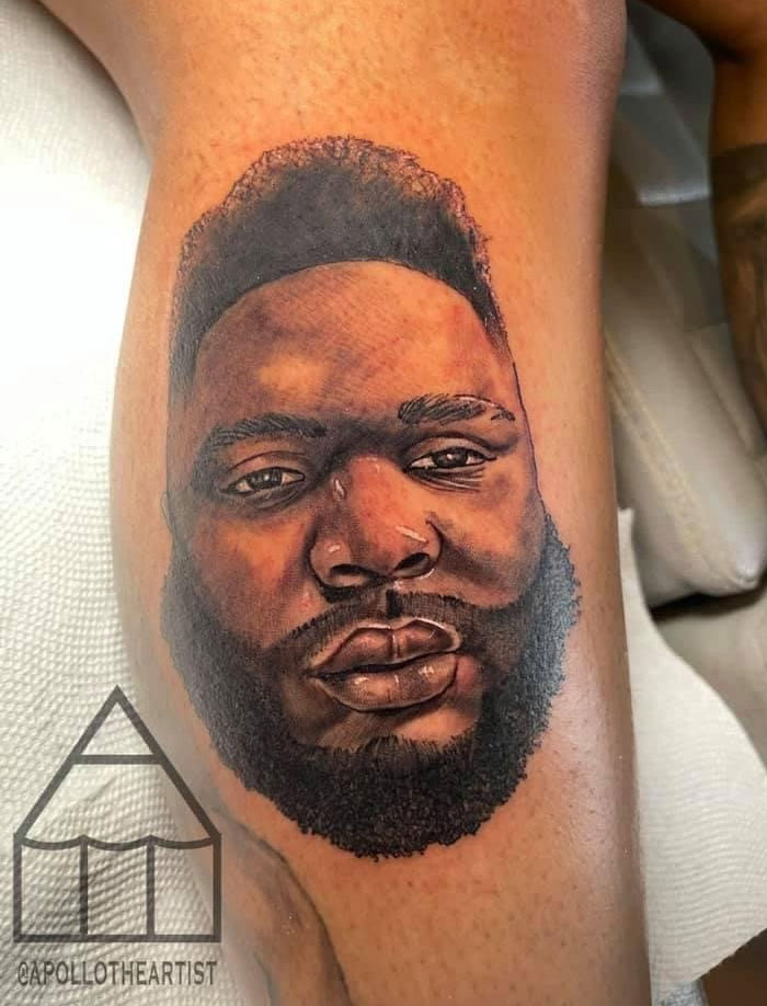 A close-up of a realistic portrait tattoo of a man's face with a beard, on a person's leg. This meaningful tattoo honors a special person.