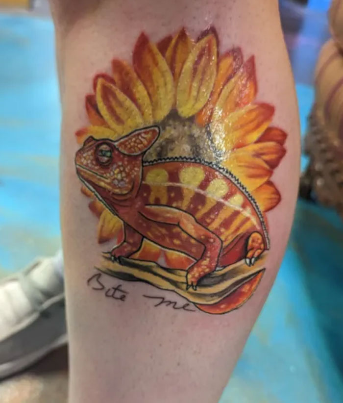 A colorful chameleon tattoo with a sunflower background and the words 'Bite me', an example of meaningful tattoos.