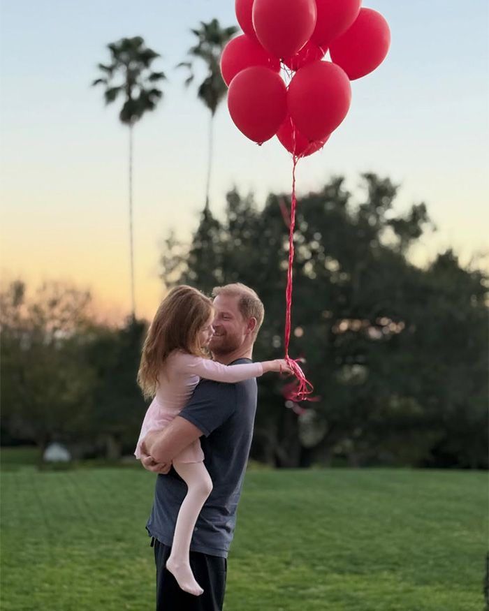 Man holding child with red balloons in outdoor park at sunset Meghan Markle kids