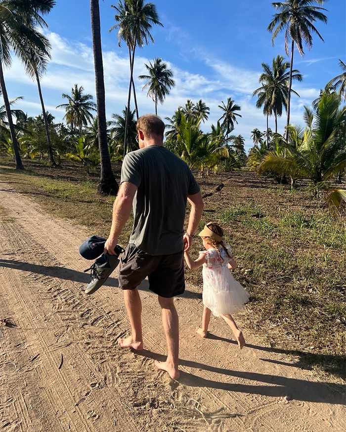 Prince Harry walking barefoot with daughter on tropical path among palm trees Meghan Markle kids
