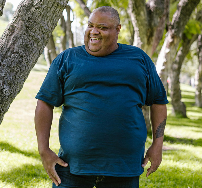 Smiling man standing in park near trees