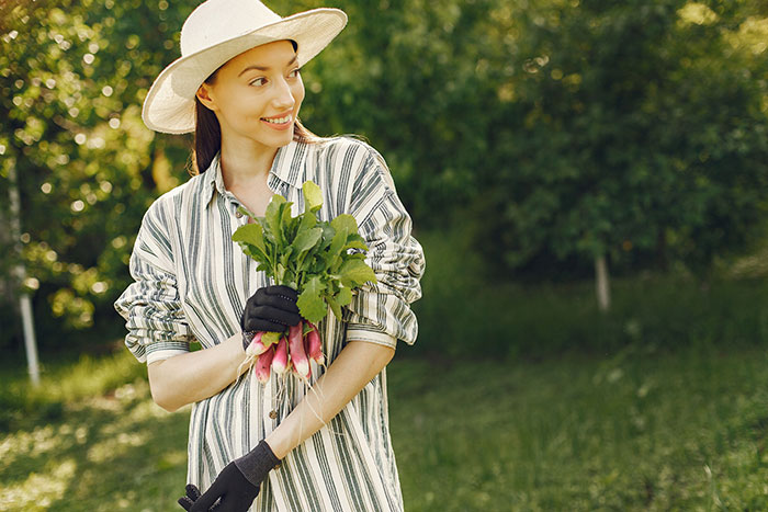 Woman holding fresh radishes smiling in garden