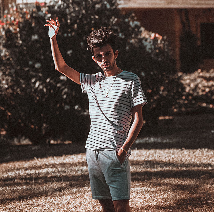 Young man standing outdoors waving wearing striped t-shirt