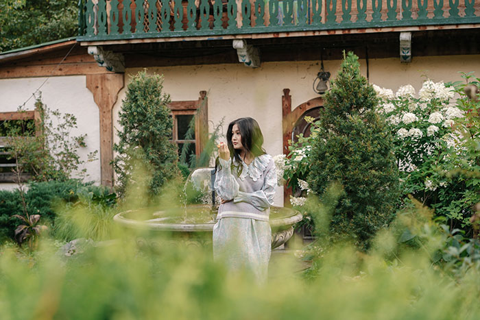 Woman in garden near fountain enjoying peaceful outdoor moment