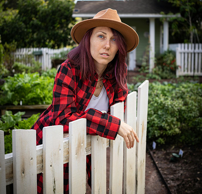Young woman in hat leaning on fence in garden for free therapist moments