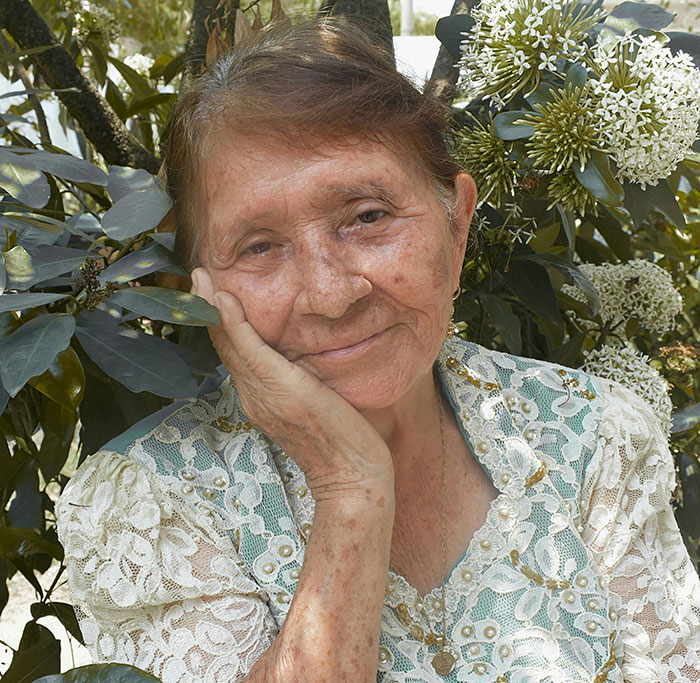 Elderly woman smiling gently among flowers for free therapist reflections