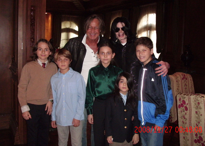 Michael Jackson with children and an adult inside a dark wood-paneled room at Neverland Ranch