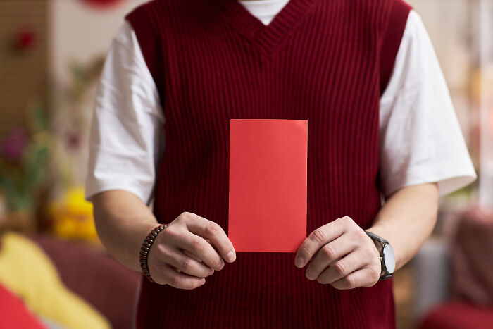 A person in a red vest holds a red envelope, symbolizing moments women decide to marry their partner.