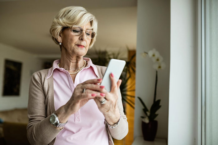 A senior woman, a MIL, on her phone, looking serious as she tries to have the final say on her grandchild's baby name.