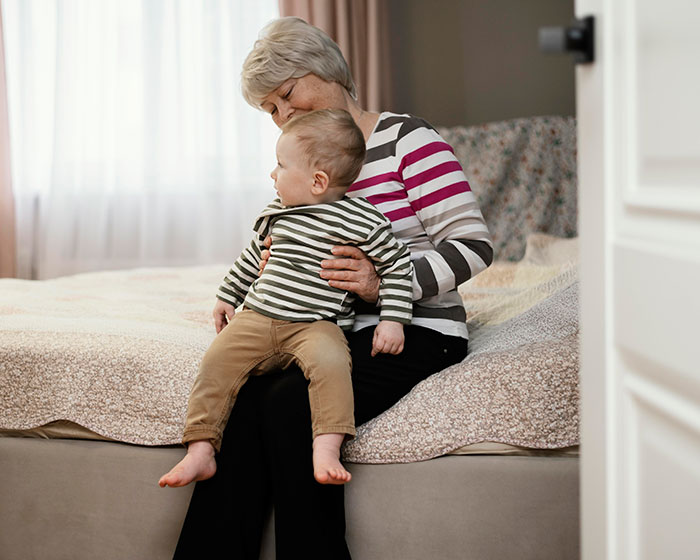 A grandmother is holding a toddler while refusing to leave during a family vacation argument. A grandmother is holding a toddler while refusing to leave during a family vacation argument.