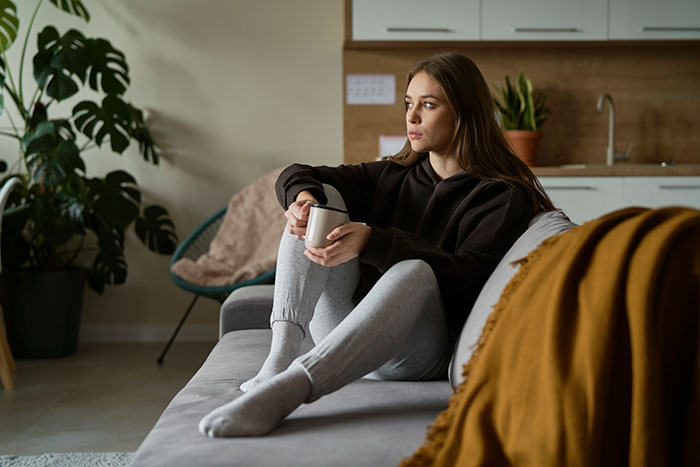 A woman looking contemplative on a couch, related to a grandma's fit and family vacation argument. A woman looking contemplative on a couch, related to a grandma's fit and family vacation argument.
