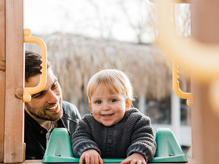Toddler smiles happily with an adult in the background, contrasting with the theme of Grandma throws a fit. Toddler smiles happily with an adult in the background, contrasting with the theme of Grandma throws a fit.
