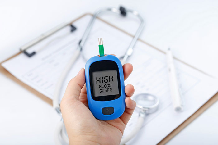 Hand holding a glucometer showing high blood sugar, relevant to entitled MIL and grandson's insulin needs.