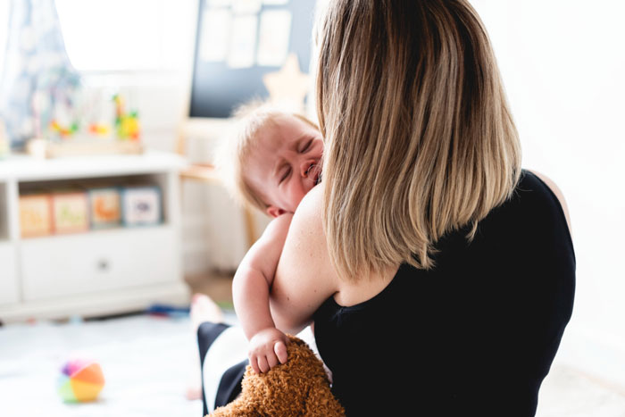 A crying baby being held by a woman, depicting the challenges of a special Mother's Day ruined by an attention-seeker. A crying baby being held by a woman, depicting the challenges of a special Mother's Day ruined by an attention-seeker.
