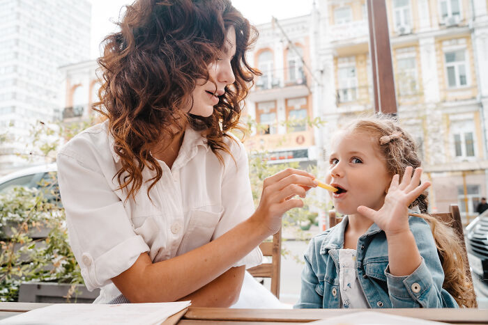 Woman feeding child fries outdoors showing moments of pure generosity