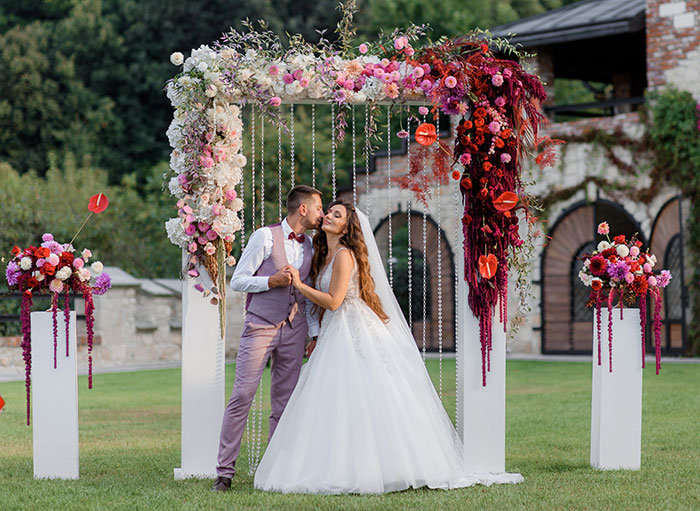 A happy couple at their wedding, under a beautiful floral arch, celebrating their union.
