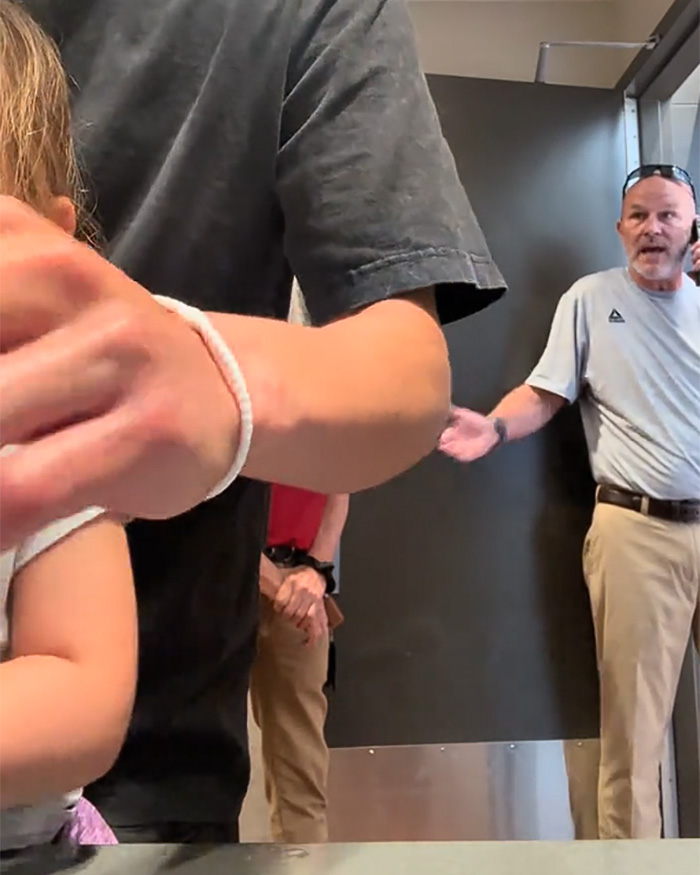 A man with a child in a restroom, confronting a Male Karen on the phone during a viral restroom video. A man with a child in a restroom, confronting a Male Karen on the phone during a viral restroom video.