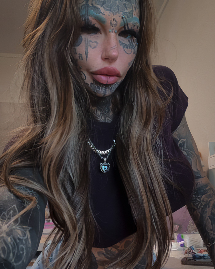 Most tattooed woman with extensive face and body tattoos poses for selfie