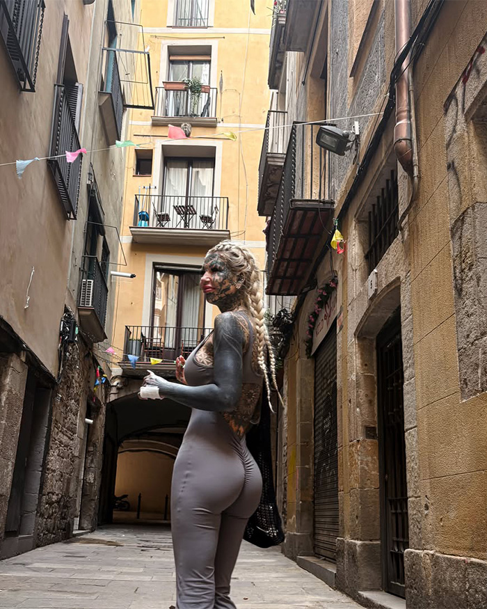 Most tattooed woman with full-body tattoos and braids posing in European street