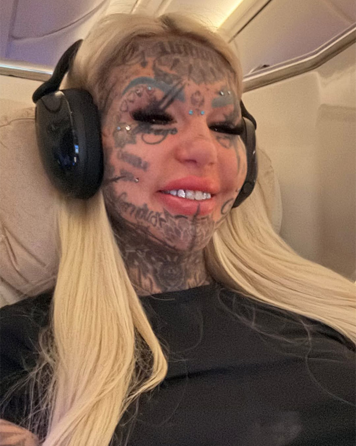 Most tattooed woman with facial tattoos wearing headphones on flight