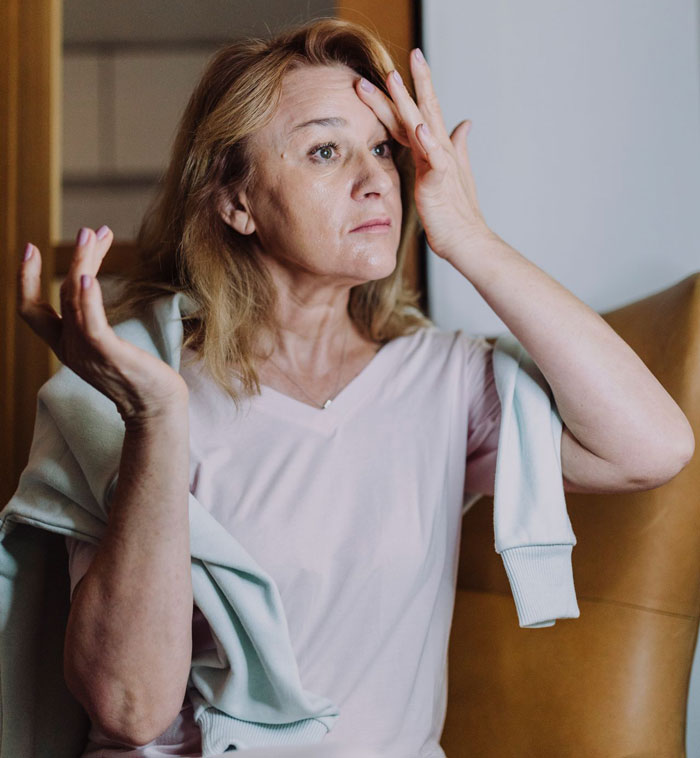 A woman with blonde hair in a pink shirt looks frustrated, with her hands near her face, expressing gluten free food surprise.