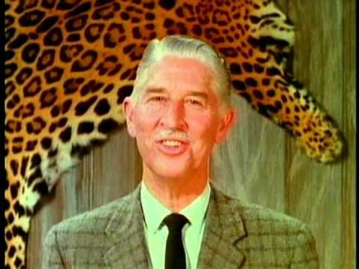 An older gentleman in a suit and tie smiling, with a leopard print background, taking you way back and reminding you how old you are.