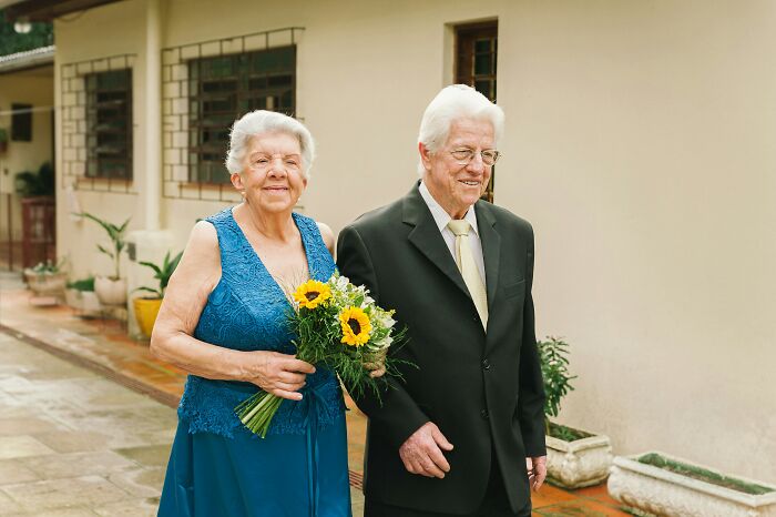 Elderly couple smiling and holding flowers at family event