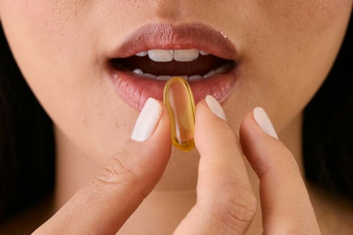 A woman taking a supplement, focused on avoiding intense stress and burnout for better health.