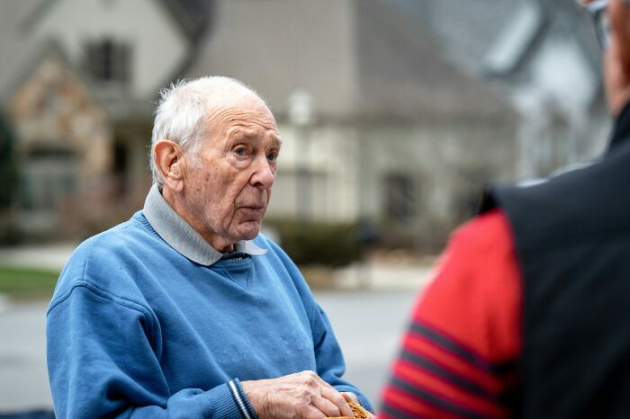 Elderly man in blue sweater talking outside near neighborhood
