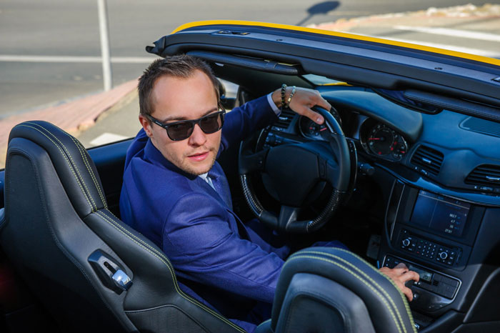 A man in a blue suit and sunglasses sits in his car, looking at the anxious neighbor complaining about his car. A man in a blue suit and sunglasses sits in his car, looking at the anxious neighbor complaining about his car.
