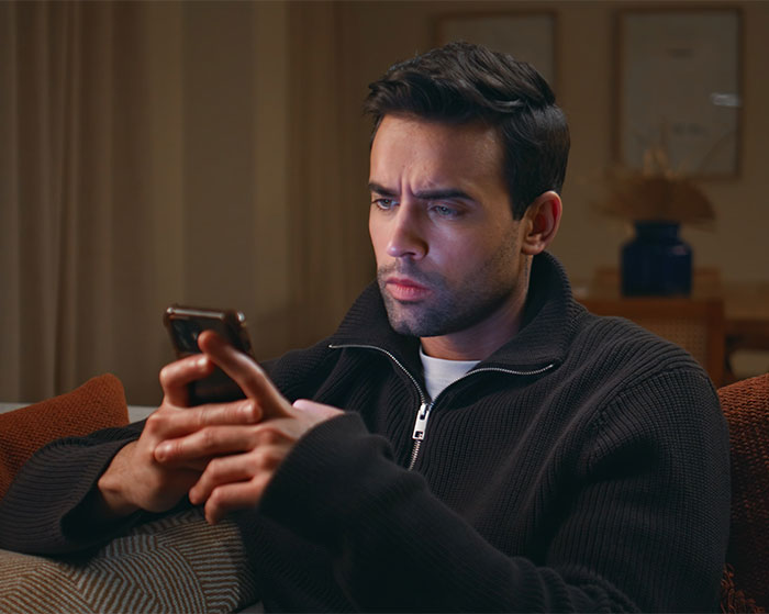 A man looking intently at his phone, possibly planning to annoy his insecure neighbor with his audacity.