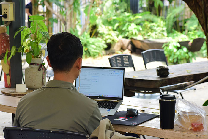 A man works on a laptop outdoors, symbolizing the man's reaction to his insecure neighbor.