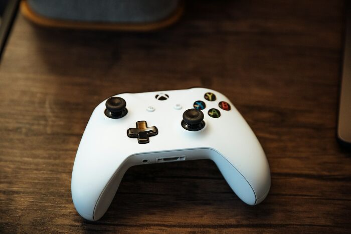 White wireless gaming controller on wooden table for distraction and relaxation