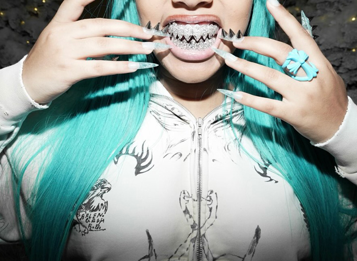 Person with turquoise hair showing silver spiked grills and long nails Person with turquoise hair showing silver spiked grills and long nails