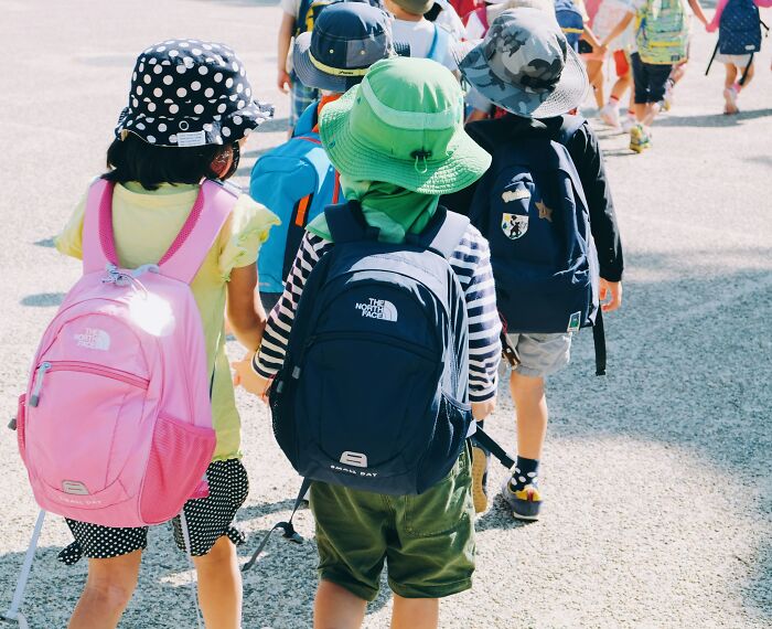 Teachers guide young students with backpacks, highlighting the challenges teachers face with entitled parents and their messages.