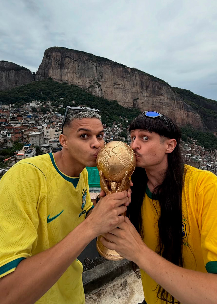 Two men in Brazil soccer jerseys kissing a golden World Cup trophy on a rooftop Two men in Brazil soccer jerseys kissing a golden World Cup trophy on a rooftop