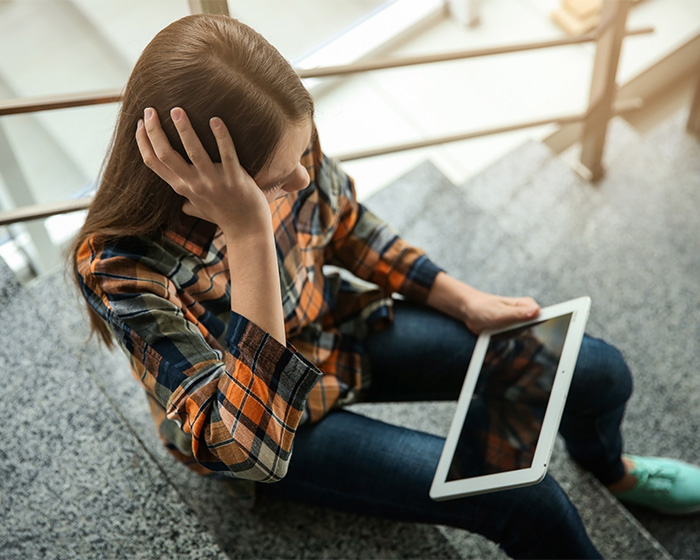 A woman looking traumatized and holding her head, after discovering old classmate's fake photos. A woman looking traumatized and holding her head, after discovering old classmate's fake photos.
