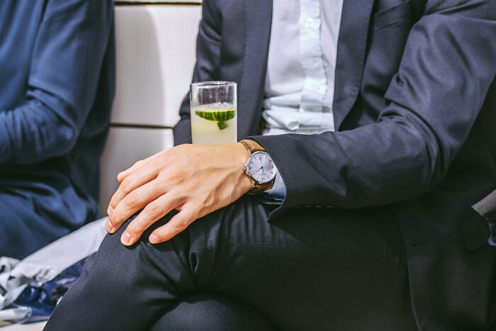 Business passenger sitting in airplane cabin with watch and drink