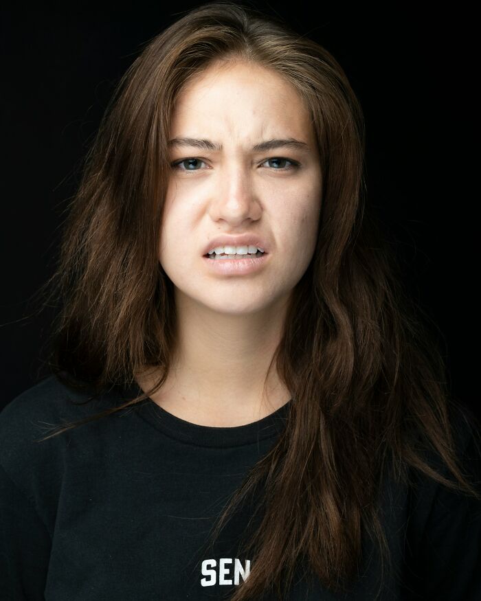 A young woman with a disgusted expression, furrowed brow, and bared teeth, looking at things found on her partners phone.