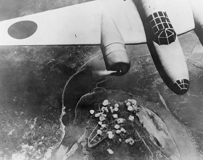 Black and white aerial photo of a World War II Japanese bomber over a target