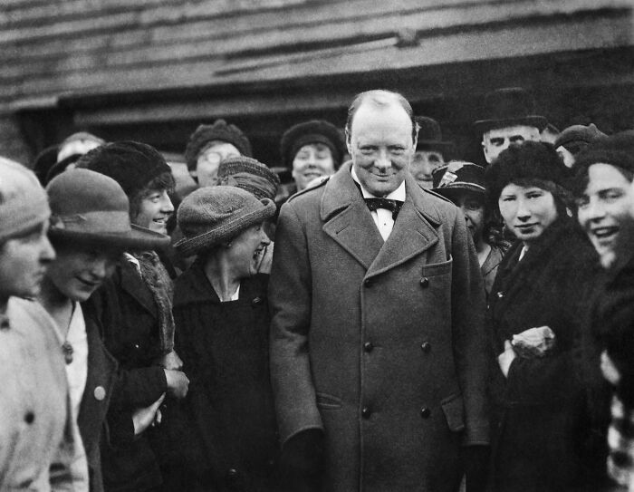 Historical black and white photo of Winston Churchill smiling with a crowd from history