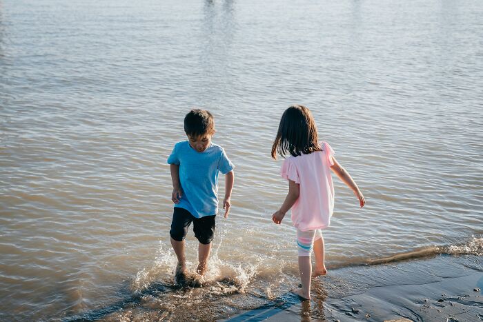 Children playing and splashing in shallow water by the beach on a sunny day