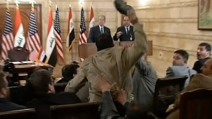 A man throwing a shoe towards a podium during a press conference, highlighting celebrity scandals.