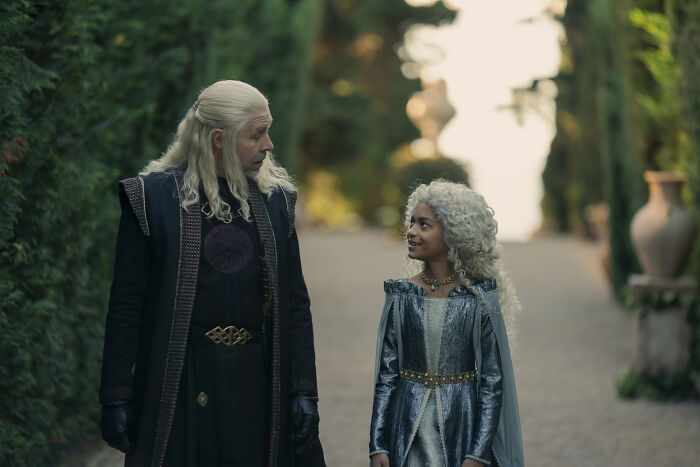A man with long white hair and a young girl with white hair walk through a garden in House Of The Dragon, a disturbing moment.