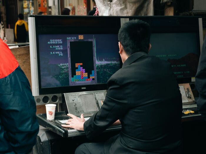 A person playing an arcade game, illustrating useless facts about video game history and culture.