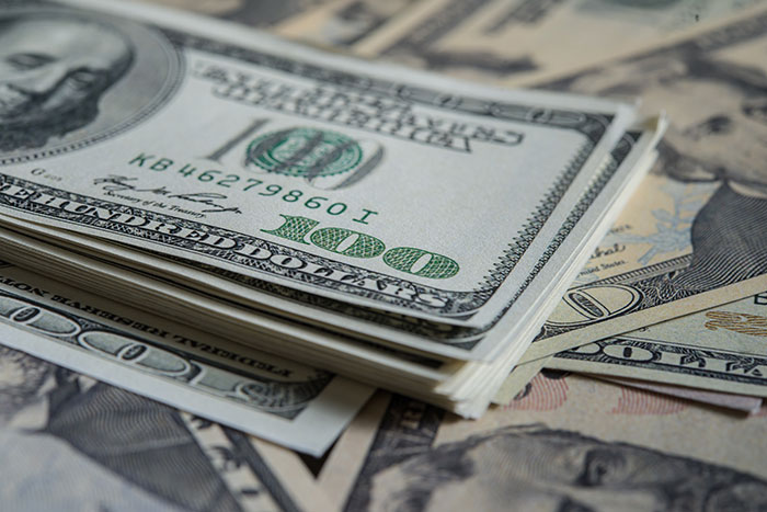 Stack of hundred dollar bills with other denominations blurred in background, relating to Walmart shoppers paying for groceries. Stack of hundred dollar bills with other denominations blurred in background, relating to Walmart shoppers paying for groceries.