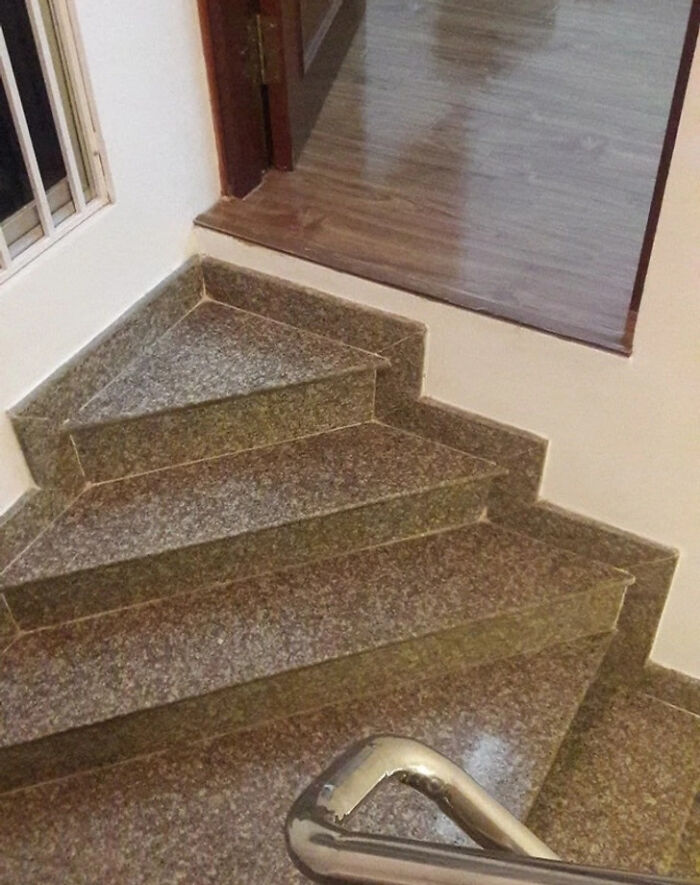 An oddly designed, triangular-shaped staircase with an upstairs landing, highlighting a ridiculous construction fail.