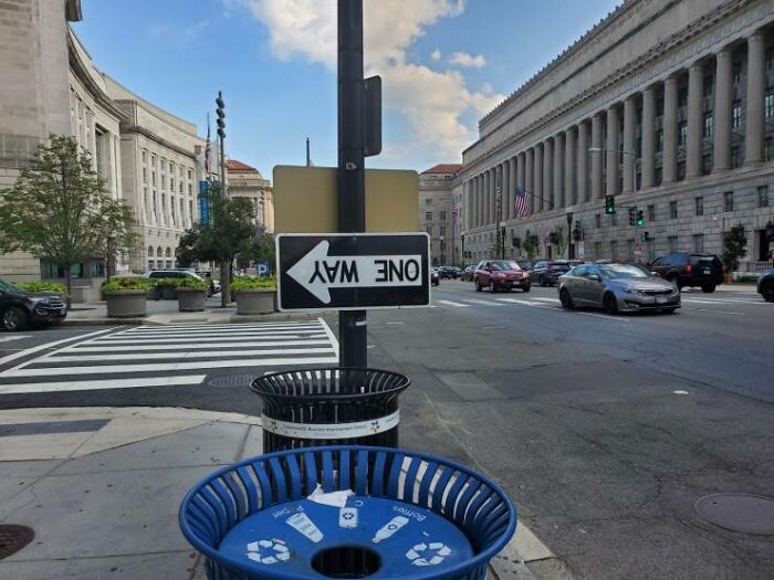 A street sign indicating a one-way street, but installed upside down, showcasing a one job fail.